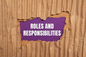 Roles and responsibilities message written on ripped torn cardboard paper on purple background. Conceptual roles and responsibilities symbol. Copy space. photo