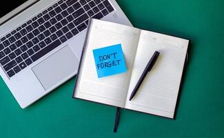 sticker reminder don't forget in notebook, laptop and notebook on beautiful green background photo