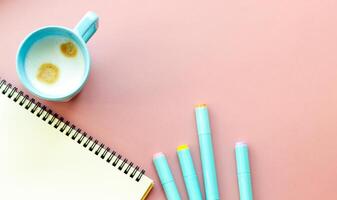 Perfect for themes related to education, art, and office aesthetic, pastel colors. colored highlighters, sketchbook, coffee mug on a plain pink background photo