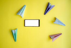 paper airplanes chaotically circle around the phone. abstraction on the theme of messages and communication photo