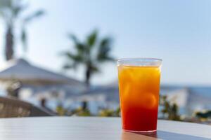 refreshing bright cocktail with ice against the backdrop of sun loungers and the sea photo