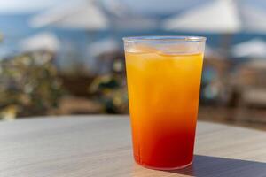 refreshing bright cocktail with ice against the backdrop of sun loungers and the sea photo