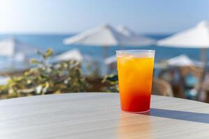 refreshing bright cocktail with ice against the backdrop of sun loungers and the sea photo