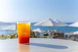 refreshing bright cocktail with ice against the backdrop of sun loungers and the sea photo
