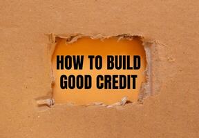 How to build good credit message written on ripped torn cardboard paper with orange background. Conceptual how to build good credit symbol. Copy space. photo