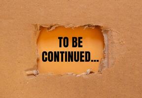 To be continued message written on ripped torn cardboard paper with orange background. Conceptual to be continued symbol. Copy space. photo