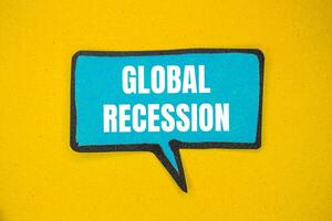 Global recession message written on blue paper speech bubble with yellow background. Conceptual global recession symbol. Copy space. photo