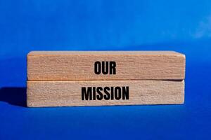 Our mission message written on wooden blocks with blue background. Conceptual our mission symbol. Copy space. photo