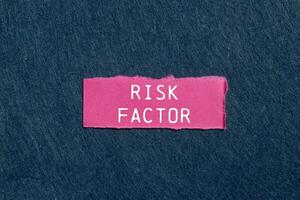 Risk factor message written on ripped pink torn paper piece on gray background. Conceptual risk factor symbol. Copy space. photo