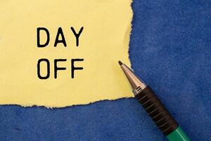 Day off message written on ripped torn yellow paper with a pen on blue background. Conceptual day off symbol. Copy space. photo