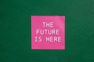 The future is here message written on ripped torn pink paper on green background. Conceptual the future is here symbol. Copy space. photo