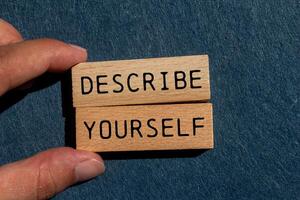 Describe yourself message written on wooden blocks on gray felt background. Conceptual describe yourself symbol. Copy space. photo
