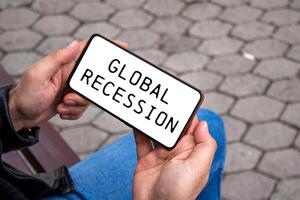 Global recession message written on smartphone screen. Conceptual global recession symbol. Copy space. photo
