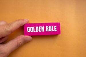 Golden rule message written on pink wooden block with orange background. Conceptual golden rule symbol. Copy space. photo