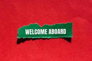 Welcome aboard message written on ripped torn green paper piece with red background. Conceptual welcome aboard symbol. Copy space. photo