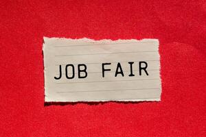 Job fair message written on ripped torn paper piece on red background. Conceptual job fair symbol. Copy space. photo