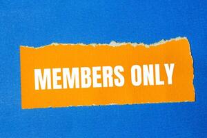Members only message written on ripped torn orange paper with blue background. Conceptual members only symbol. Copy space. photo