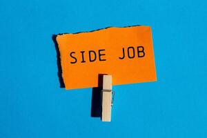 Side job message written on ripped torn orange paper on blue background. Conceptual side job symbol. Copy space. photo