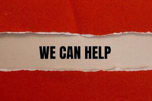 We can help message written on ripped red torn paper with beige background. Conceptual we can help symbol. Copy space. photo