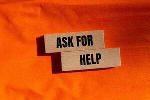 Ask for help message written on wooden blocks with orange background. Conceptual ask for help symbol. Copy space. photo