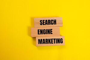 Search engine marketing message written on wooden blocks with yellow background. Conceptual search engine marketing symbol. Copy space. photo
