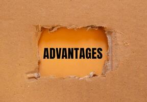 Advantages message written on ripped torn cardboard paper with orange background. Conceptual advantages symbol. Copy space. photo