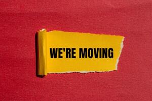 We are moving message written on ripped torn yellow paper with red background. Conceptual we are moving symbol. Copy space. photo