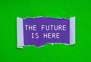 The future is here message written on ripped torn green paper on purple background. Conceptual the future is here symbol. Copy space. photo