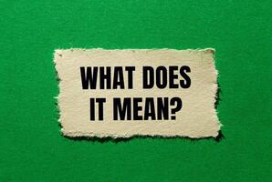 What does it mean question written on ripped torn paper piece on green background. Conceptual what does it mean question symbol. Copy space. photo