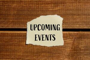 Upcoming events message written on ripped torn paper with wooden background. Conceptual upcoming events symbol. Copy space. photo