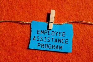 Employee assistance program message written on ripped blue torn paper piece on orange background. Conceptual employee assistance program symbol. Copy space. photo