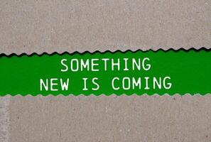 Something new is coming message written on ripped torn paper on green background. Conceptual something new is coming symbol. Copy space. photo