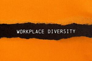 Workplace diversity message written on ripped torn orange paper on black background. Conceptual workplace diversity symbol. Copy space. photo