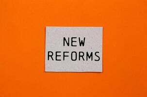 New reforms message written on paper piece with orange background. Conceptual new reforms symbol. Copy space. photo