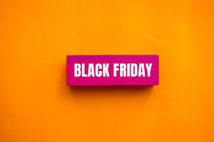 Black friday message written on pink wooden block with orange background. Conceptual black friday symbol. Copy space. photo
