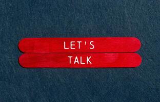 Let's talk message written on red wooden sticks on gray felt background. Conceptual let's talk symbol. Copy space. photo