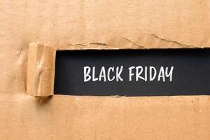 Black friday message written on ripped torn cardboard paper with black background. Conceptual black friday symbol. Copy space. photo