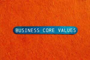 Business core values message written on blue wooden stick on orange background. Conceptual business core values symbol. Copy space. photo