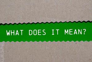 What does it mean question written on ripped torn paper on green background. Conceptual what does it mean question symbol. Copy space. photo