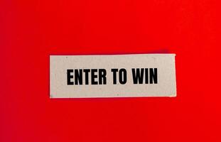 Enter to win message written on paper piece with red background. Conceptual enter to win symbol. Copy space. photo