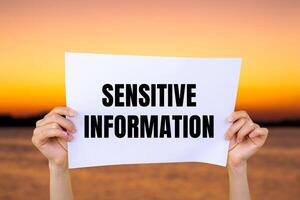 Sensitive information message written on white paper with blurry lake background. Conceptual sensitive information symbol. Copy space. photo