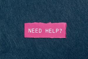 Need help question written on ripped pink torn paper piece on gray background. Conceptual need help question symbol. Copy space. photo