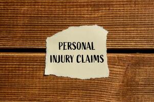 Personal injury claims message written on ripped torn paper with wooden background. Conceptual personal injury claims symbol. Copy space. photo