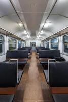 interior of an cheap empty train car with simple bench-style seating. The car features metal luggage racks above the windows, a clean, minimalist design, and a bright, neutral color scheme. photo