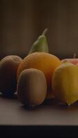 un vibrante y hermosa arreglo de varios Fresco frutas desplegado en un de madera superficie video