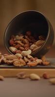 Assorted nuts spilled from a bowl onto a wooden surface, creating a colorful, nutritious snack video