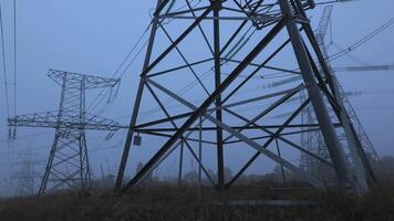 Dense fog envelops a field as power lines loom in the ethereal twilight. The stillness captures the contrast between nature and energy infrastructure. video