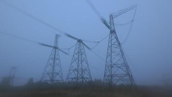 Thick fog blankets the landscape, creating a surreal atmosphere around towering power lines at dawn. The quiet morning brings an eerie beauty to the scene. video