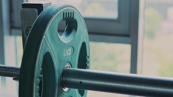 Powerlifting workout. Athlete adding weight plates on barbell before exercising at gym, close up video