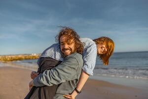 Smilng couple in love fool around while walking along the beach on sunny windy day photo